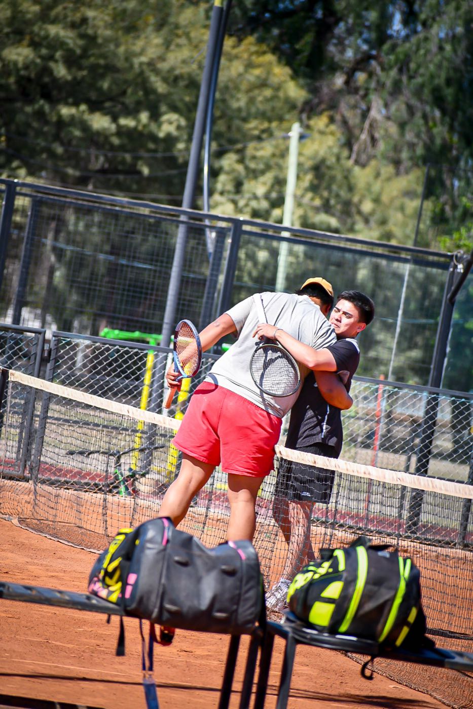 Compañeros de dobles se abrazan junto a la red después del punto